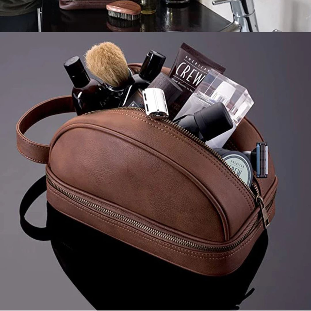 Une trousse de toilette homme en cuir marron est ouverte sur une surface noire, remplie de produits de soins, d'un blaireau, de petites bouteilles et d'un tube, suggérant une trousse de toilette ou de voyage pour hommes.