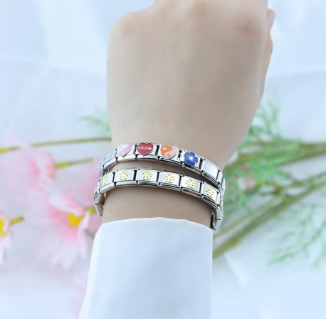  Une main féminine tenant un bracelet-charms-Italien orné de pierres colorées, mettant en valeur la beauté et l'élégance des accessoires.