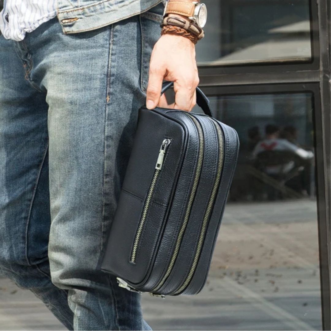 Homme portant une Trousse de toilette homme luxe noire, en cuir, au design chic et pratique.
