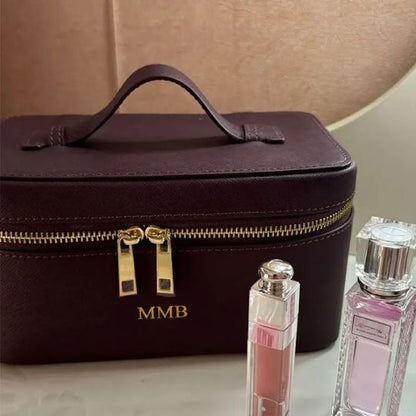 Trousse de maquillage bordeaux personnalisée avec initiales dorées et cosmétiques élégants.