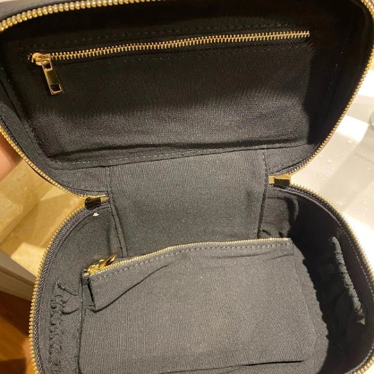 Trousse de maquillage noire ouverte avec fermetures éclair dorées et doublure noire.