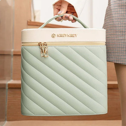 Une main tient une élégante malette de maquillage turquoise et crème.