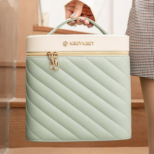 Une main tient une élégante malette de maquillage turquoise et crème.